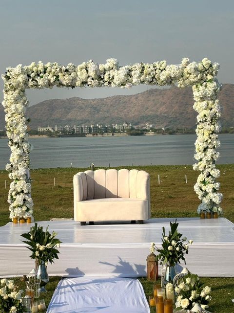 White floral wedding stage with Udaisagar lake behind at The Udaisarovar